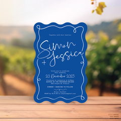 Wave shape flat lay of semi-custom Vino wedding invitation with hand-drawn vineyard-inspired border.