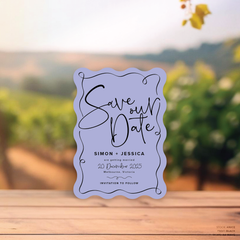 Wave shape flat lay of semi-custom Vino wedding save the date with hand-drawn vineyard-inspired border.