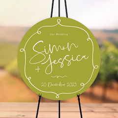 Round shape flat lay of semi-custom Vino wedding welcome sign with hand-drawn vineyard-inspired border.