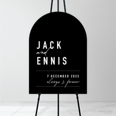 Arch shape flat lay of Never Let You Go wedding welcome sign featuring bold and delicate typography with modern, expressive layout and semi-custom design.